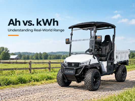 White LLAMA electric utility truck parked on a rural farm road, illustrating the difference between battery amp-hours (Ah), kilowatt-hours (kWh), and real-world driving range.