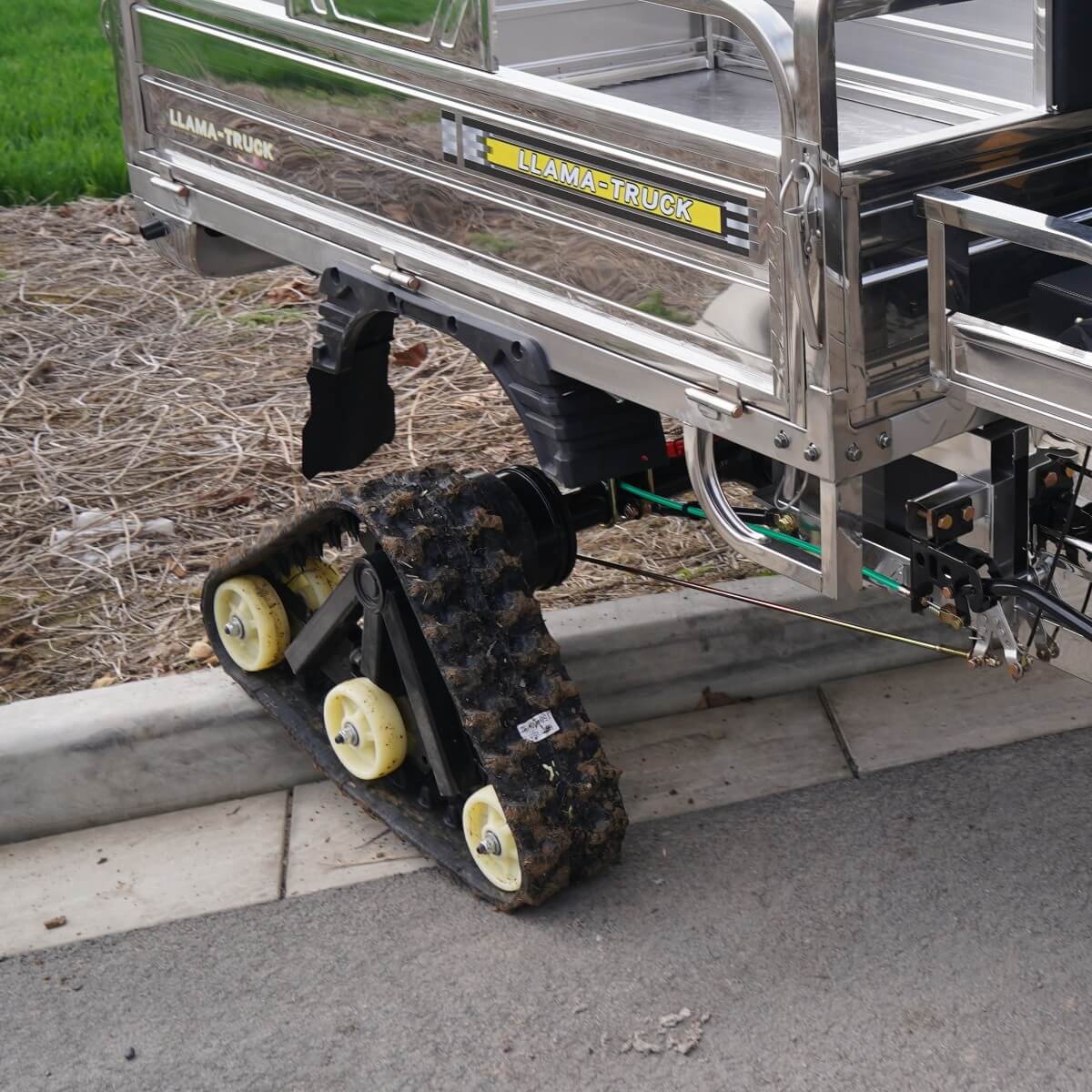 Llama Truck rubber tracks climbing over a concrete curb showing high clearance.