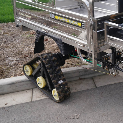 Llama Truck rubber tracks climbing over a concrete curb showing high clearance.
